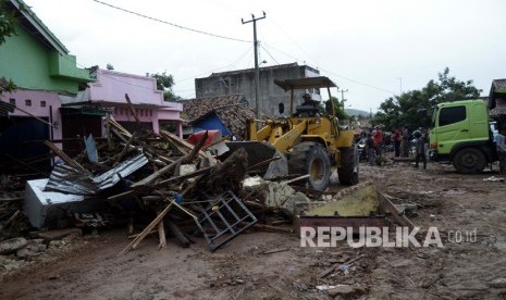 Petugas dengan menggunakan alat berat membersihkan sisa-sisa bangunan yang tersapu tsunami di jalan Desa Way Muli, Kecamatan Rajabasa, Lampung Selatan, Lampung, Ahad (23/12/2018). 