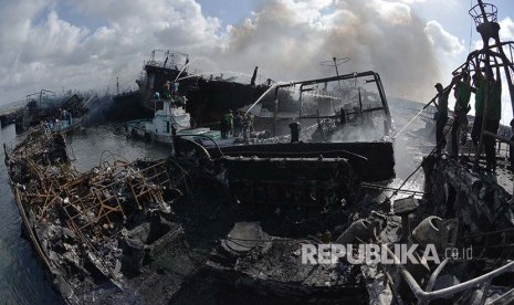 Petugas dibantu warga berusaha melakukan upaya pendinganan kapal ikan yang terbakar di Pelabuhan Benoa, Denpasar, Bali, Senin (9/7). 