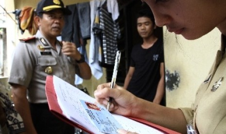 Petugas Dinas kependudukan dan catatan sipil dibantu pihak kepolisian saat melakukan operasi yustisi.