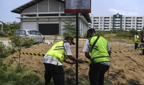 Petugas Dinas Lingkungan Hidup DKI Jakarta memasang tali pembatas dan papan peringatan di dekat gundukan tanah yang diduga tercemar limbah B3 di kawasan Marunda, Jakarta, Rabu (9/1/2019). 