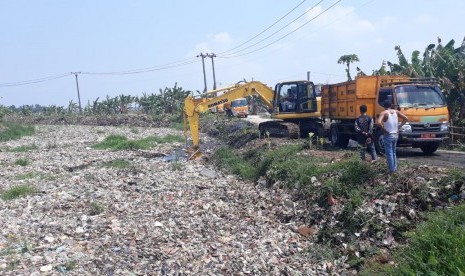 Petugas Dinas Lingkungan Hidup (DLH) Kabupaten Bekasi mengangkut sampah yang menumpuk di Kali Pisang Batu, Desa Pahlawan Setia, Kecamatan Tarumajaya, Kabupaten Bekasi, Ahad (6/1).