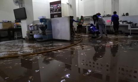 Petugas Dinas Pemadam Kebakaran dibantu warga membersihkan lumpur usai banjir merendam rumah pribadi Bupati Jember Hendy Siswanto di Kecamatan Kaliwates, Jember, Jawa Timur, Senin (17/1/2022). Banjir merendam rumah pribadi bupati Jember dan puluhan rumah di sekitarnya dengan ketinggian satu meter akibat luapan Sungai Jompo setelah hujan deras mengguyur Jember selama lebih dari tiga jam.