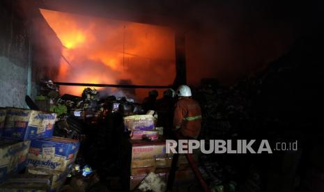 Petugas Dinas Pemadam Kebakaran Kota Surabaya memadamkan gudang yang terbakar di Jalan Sidotopo Kidul, Surabaya, Jawa Timur, Kamis (30/9/2021). Sebanyak 18 unit kendaraan pemadam kebakaran dikerahkan untuk memadamkan kebakaran satu gudang kayu dan satu gudang penyimpanan mie instan serta produk pangan lainnya tersebut.