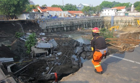 Petugas Dinas Pemadam Kebakaran Kota Surabaya memeriksa lokasi tanah ambles di Jalan Raya Gubeng, Surabaya, Jawa Timur, Rabu (19/12/2018).