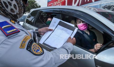 Petugas gabungan memeriksa surat pengguna kendaraan yang masuk ke wilayah DKI Jakarta di kawasan perbatasan Bekasi-Karawang, Jawa Barat, Jumat (29/5/2020). 