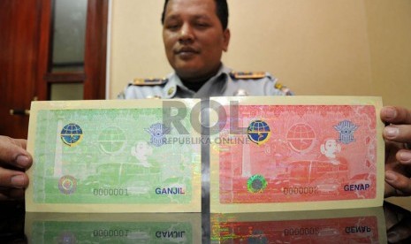   Petugas Dinas Perhubungan DKI Jakarta menunjukkan stiker ganjil genap berhologram di Jakarta, Kamis (7/3).   (Republika/Prayogi)