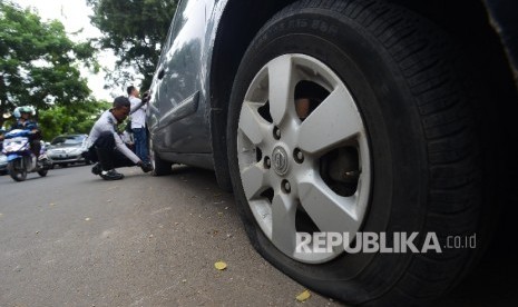 Petugas Dinas Perhubungan mengempeskan sebuah mobil yang terparkir liar di Jalan Bungur Besar, Jakarta Pusat, Rabu (23/3). 