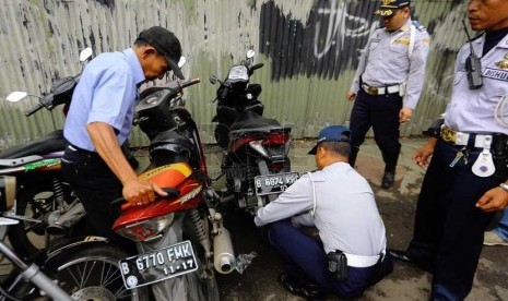   Petugas Dishub DKI mencabut pentil ban motor dan mobil yang parkir sembarangan di Jalan Matraman, Jakarta Timur, Senin (10/3).   (Republika/Yasin Habibi)