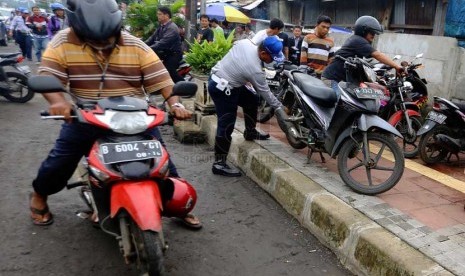   Petugas Dishub DKI mencabut pentil ban motor dan mobil yang parkir sembarangan di Jalan Matraman, Jakarta Timur, Senin (10/3).   (Republika/Yasin Habibi)