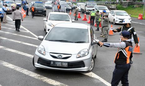 Petugas gabungan dari Dishub Kota Bogor, Satpol PP Kota Bogor, Polisi Militer dan Polresta Bogor Kota mengarahkan kendaraan roda empat berplat ganjil untuk memutar balik saat pemberlakuan aturan ganjil-genap di pos sekat Gerbang Tol Bogor, Tanah Baru, Kota Bogor, Jawa Barat.