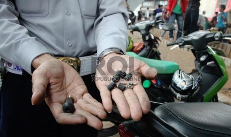   Petugas gabungan dari Suku Dinas Perhubungan dan Satlantas Jakarta Pusat menunjukkan pentil ban saat melakukan penertiban parkir kendaraan liar di badan jalan dan trotoar di bawah jalan layang Roxy, Jakarta, Selasa (17/9).     (Republika/Yasin Habibi)