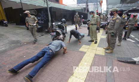 Petugas gabungan memberikan hukuman push up kepada warga yang tidak memakai masker saat razia Pembatasan Sosial Berskala Besar(PSBB) di Kawasan Jalan Fatmawati, Jakarta, Selasa (28/4/2020). Penertiban tersebut terkait pelaksanaan Pembatasan Sosial Berskala Besar(PSBB) di wilayah Jakarta dan memutus rantai penyebaran COVID 19.