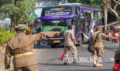 Petugas gabungan mengarahkan bus yang membawa pemudik dari arah Bekasi menuju Karawang untuk berputar arah di Perbatasan Karawang - Bekasi, Jawa Barat, Jumat (24/4/2020). Dari pemantauan yang dilakukan Kemenhub di Posko Gerbang Tol Cikarang Barat sejak 27 April 2020 hingga 6 Mei 2020 terjadi rata-rata penurunan jumlah kendaraan yang dialihkan sebesar 26 persen. 