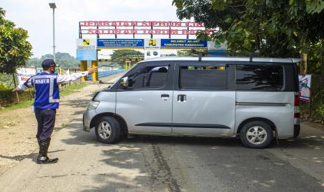 Petugas gabungan mengarahkan pemudik roda empat yang akan melewati titik pemeriksaan untuk berputar arah di perbatasan Bekasi - Karawang, Jembatan Siphon, Telukjambe Barat, Karawang, Jawa Barat, Rabu (6/5/2020). Petugas gabungan memperketat akses keluar masuk kendaraan yang melewati perbatasan pada hari pertama pemberlakuan Pembatasan Sosial Berskala Besar (PSBB) di Karawang.