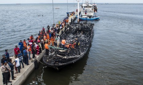 Petugas gabungan mengevakuasi korban yang terbakar di dalam kapal motor Zahro Express di dermaga Muara Angke, Jakarta, Ahad (1/1).