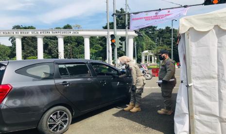 Petugas gabungan menghentikan kendaraan yang melanggar sistem ganjil-genap di Tugu Kujang, Kota Bogor, Jumat (12/2).