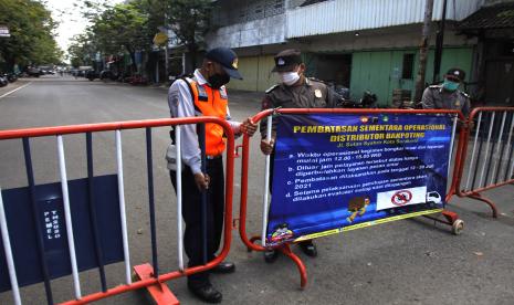 Petugas gabungan menutup akses Jalan Sutan Syahrir di Simpang Empat Pasar Legi, Solo, Jawa Tengah, Selasa (13/7/2021). Penutupan jalan tersebut merupakan upaya penegakan aturan PPKM Darurat untuk mengurangi mobilitas warga dan pembatasan sementara kegiatan operasional distribusi barang kebutuhan pokok dan barang penting di pasar setempat.