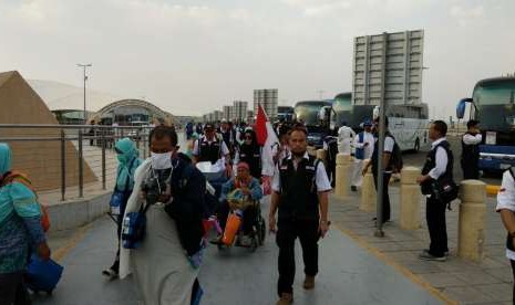 Petugas Haji Daker Bandara menuntun jamaah Kloter 63 Debarkasi Jakarta-Bekasi menuju paviliun Bandara Amir Muhammad bin Abdulaziz, Madinah, Selasa (25/9). Kloter tersebut merupakan kloter terakhir yang dipulangkan ke Tanah Air pada musim haji tahun ini.