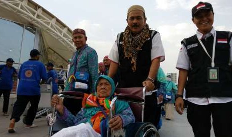 Petugas Haji Daker Bandara menuntun jamaah Kloter 63 Debarkasi Jakarta-Bekasi menuju paviliun Bandara Amir Muhammad bin Abdulaziz, Madinah, Selasa (25/9). Kloter tersebut merupakan kloter terakhir yang dipulangkan ke Tanah Air pada musim haji tahun ini.