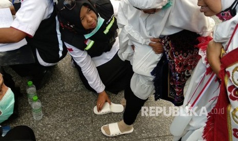 Petugas haji Indonesia memakaikan sandal pada jamaah yang kehilangan di Gerbang 21 Masjid Nabawi, Jumat (27/7). Tim kesehatan membagikan ribuan sandal mengingat berbahayanya berjalan-jalan tanpa sandal di tengah cuaca panas Madinah.