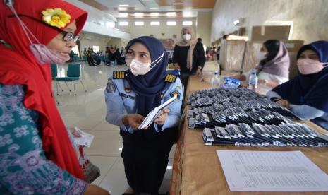 Keberangkatan Separuh Calon Jamaah Haji Lampung Tertunda. Foto:   Petugas Imigrasi Lampung menyerahkan paspor milik jamaah calon haji kelompok terbang (kloter) pertama Embarkasi Lampung di Asrama Haji Lampung, Lampung, Ahad (5/6/2022). Sebanyak 393 jamaah calon haji asal Bandar Lampung tiba di Asrama Haji Lampung dan akan diterbangkan pada Senin (6/6/2022). 