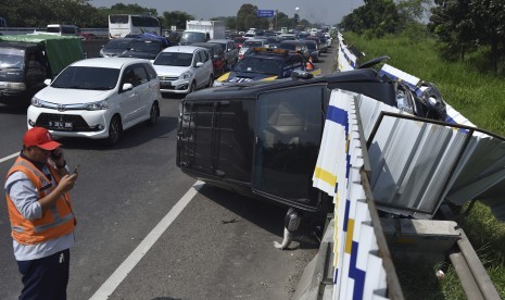 Petugas Jasa Marga mengamati kendaraan dengan nopol AA 8913 LA yang mengalami kecelakaan di Tol Cikampek KM 41, Jawa Barat, Minggu (2/7).