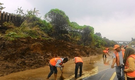 Petugas jasa marga sedang membersihkan tanah bekas longsoran di tol Cipularang. Longsor di Tol Cipularang terjadi akibat curah hujan tinggi guyur Kampung Hegarmanah, Bandung