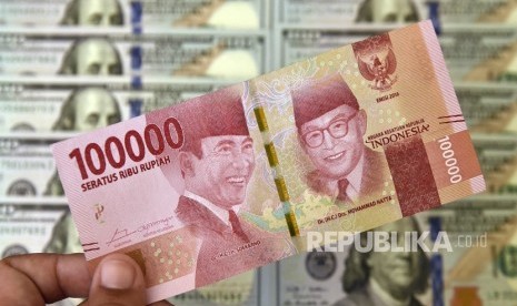 Petugas jasa penukaran valuta asing memeriksa lembaran mata uang rupiah dan dolar AS. ilustrasi