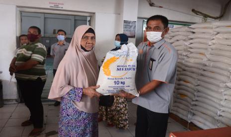 Petugas (kanan) menyerahkan bantuan beras kepada warga saat penyaluran di Kantor PT POS Indonesia, Banda Aceh, Aceh, Senin (26/7/2021). Pada masa Pemberlakuan Pembatasan Kegiatan Masyarakat (PPKM), pemerintah menyalurkan Bantuan Sosial Tunai (BST) dan Program Keluarga Harapan (PKH) kepada masing masing 10 juta penerima plus sebanyak 10 kilogram beras.