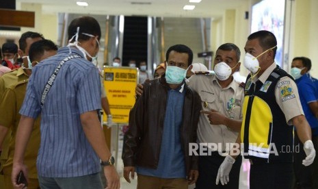 Petugas Kantor Kesehatan Pelabuhan (KKP) memasangkan masker dilanjutkan pemeriksaan kesehatan terhadap mahasiswa asal Aceh, Muhammad Sahuddin (ketiga kanan) seusai perjalanan dari China di Bandara Internasional Sultan Iskandar Muda, Aceh Besar, Aceh, Selasa (28/1/2020).