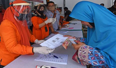 Petugas Kantor Pos menyerahkan bukti verifikasi pemberian bantuan sosial tunai (BST) kepada warga penerima manfaat di Kantor Pos Serang, Banten, Rabu (6/5/2020). Bansos berupa uang tunai Rp600 ribu per KK per bulan diberikan kepada keluarga miskin dan rentan miskin dampak pandemi COVID-19 selama tiga bulan ke depan.