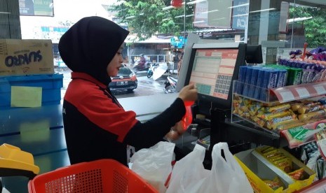 Petugas kasir Alfamidi Jl Veteran, Purwakarta, saat sedang melayani konsumennya, Rabu (6/3). 