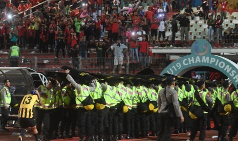 Petugas keamanan berusaha melindungi pesepak bola Malaysia U19 Mohamad Izzuddin (kiri) dari lemparan suporter Indonesia usai laga semi final Piala AFF U19 di Gelora Delta Sidoarjo, Sidoarjo, Jawa Timur, Kamis (12/7). Indonesia kalah adu pinalti dengan Malaysia dengan skor 3-4