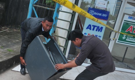 Petugas keamanan dan petugas bank mengangkat sisa mesin Anjungan Tunai Mandiri (ATM) yang dibobol maling. (Ilustrasi)