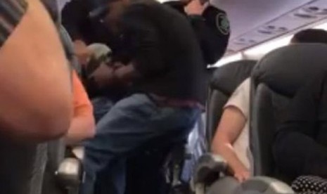 Petugas keamanan memaksa salah satu penumpang United Airlines, David Dao turun dari pesawat dengan menyeretnya, Ahad (9/4).