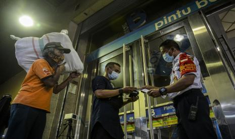 Petugas keamanan mengecek kartu vaksin pengunjung di Blok B Pasar Tanah Abang, Jakarta.