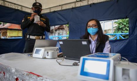 Petugas keamanan Terminal Kampung Rambutan menghembuskan nafasnya pada kantong nafas untuk dites dengan GeNose C19 di Terminal Kampung Rambutan, Jakarta.