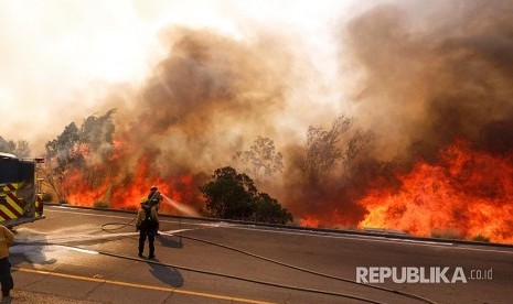 Petugas kebakaran berusaha memadamkan api di jalan Ronald Reagan, Simmi Valley, Kalifornia (12/11) waktu setempat.