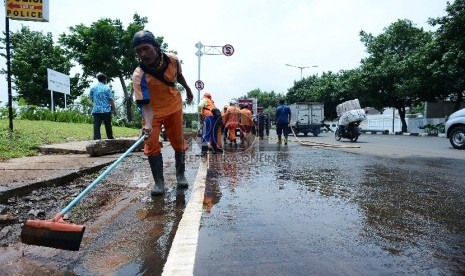 Petugas kebersihan bersama petugas pemadam kebakaran membersihkan lumpur yang mengerak akibat banjir di Kawasan Pluit, Jakarta Utara, Kamis (12/2). 