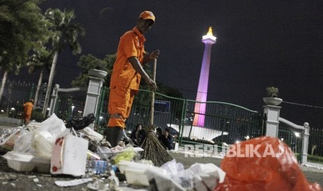  Petugas kebersihan membersihkan sisa sampah warga yang merayakan tahun baru di kawasan Monas, Jakarta Pusat, Ahad (1/1). 