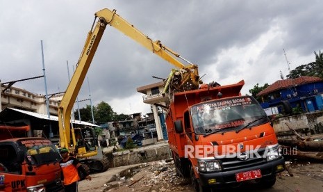 Petugas kebersihan menggunakan alat berat mebersihkan sampah pada aliran Sungai Ciliwung yang menyumbat Pintu Air Manggarai, Jakarta, Rabu (1/2)