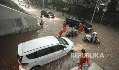 Petugas Kebersihan Pemprov DKI Jakarta mencoba membantu kendaraan yang akan melintasi genangan air yang menggenangi kawasan Semanggi di Jakarta, Senin (11/12). (Ilustrasi)