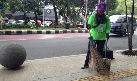 Petugas kebersihan sedang membersihkan trotoar di salah satu sudut Kota Bandung.