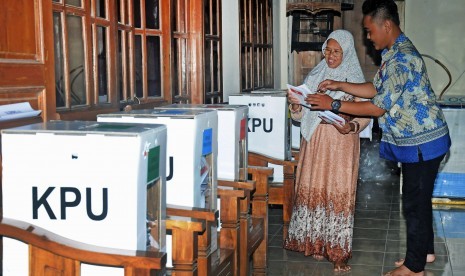 Petugas Kelompok Penyelenggara Pemungutan Suara (KPPS) membantu warga memasukkan surat suara kedalam kotak suara saat pemungutan suara ulang.