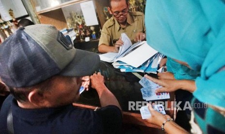 Petugas Kelurahan melayani warga saat pengambilan KTP-el di Kelurahan Bakti Jaya Depok, Jawa Barat, Senin (4/2).