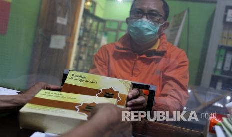 Petugas Kementerian Agama Kota Kendari (kiri) memberikan buku panduan manasik haji.