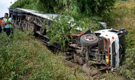 Petugas kepolisian berdiri di dekat truk kontainer bermuatan kayu seberat delapan ton nopol DK 9488 ME yang terguling setelah kehilangan kendali dan menabrak sebuah sepeda motor di Jalan Soekarno Hatta, Ungaran, Kab. Semarang, Jateng, Rabu (22/7). 