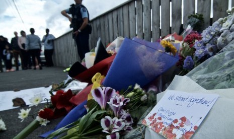 Petugas kepolisian berjaga di dekat bunga yang diletakkan warga di depan Masjid Wellington, Kilbirnie, Wellington, Selandia Baru, Sabtu (16/3/).