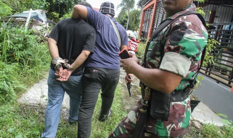 Petugas kepolisian berpakaian sipil bersama prajurit TNI menangkap salah satu tahanan yang kabur dari Rutan Sialang Bungkuk Kelas IIB, Pekanbaru, Riau, Jumat (5/5). 