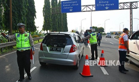 Petugas kepolisian bersama petugas Jasa Marga menghalau pengendara berpelat nomor ganjil yang akan memasuki tol Jakarta - Tangerang (Janger) saat dimulainya hari pertama uji coba penerapan sistem ganjil genap di Gerbang Tol Tangerang 2, Tangerang, Banten, Senin (16/4). 